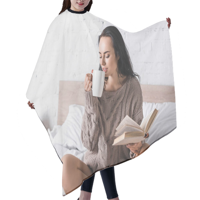 Personality  young brunette woman in sweater sitting in bed with mug of hot cocoa and book at morning hair cutting cape