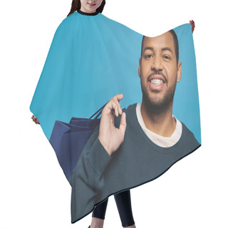 Personality  Portrait Of Cheerful African American Young Man With Shopping Bag Over Shoulder On Blue Background Hair Cutting Cape