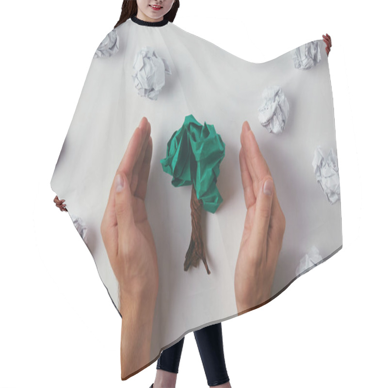 Personality  cropped shot of man covering crumpled papers in shape of tree on white surface hair cutting cape