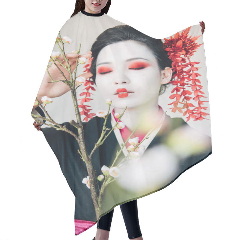 Personality  selective focus of tree branches and beautiful geisha with red and white makeup and closed eyes isolated on white hair cutting cape