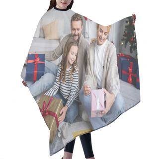 Personality  Smiling Woman Looking At Christmas Present Near Daughter And Husband With Gifts At Home  Hair Cutting Cape