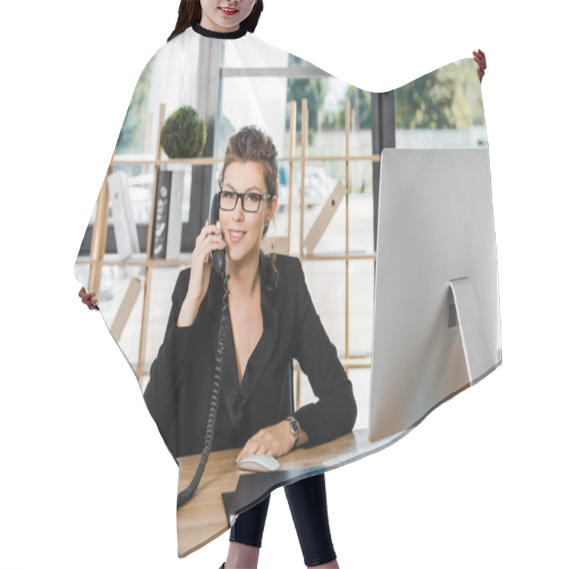 Personality  smiling attractive businesswoman talking by stationary telephone in office and looking at camera hair cutting cape