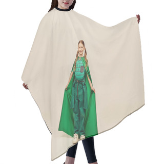 Personality  Cheerful Redhead Kid In Green Superhero Costume Holding Cape And Looking At Camera While Standing On Grey Background In Studio During International Children`s Day Celebration Hair Cutting Cape