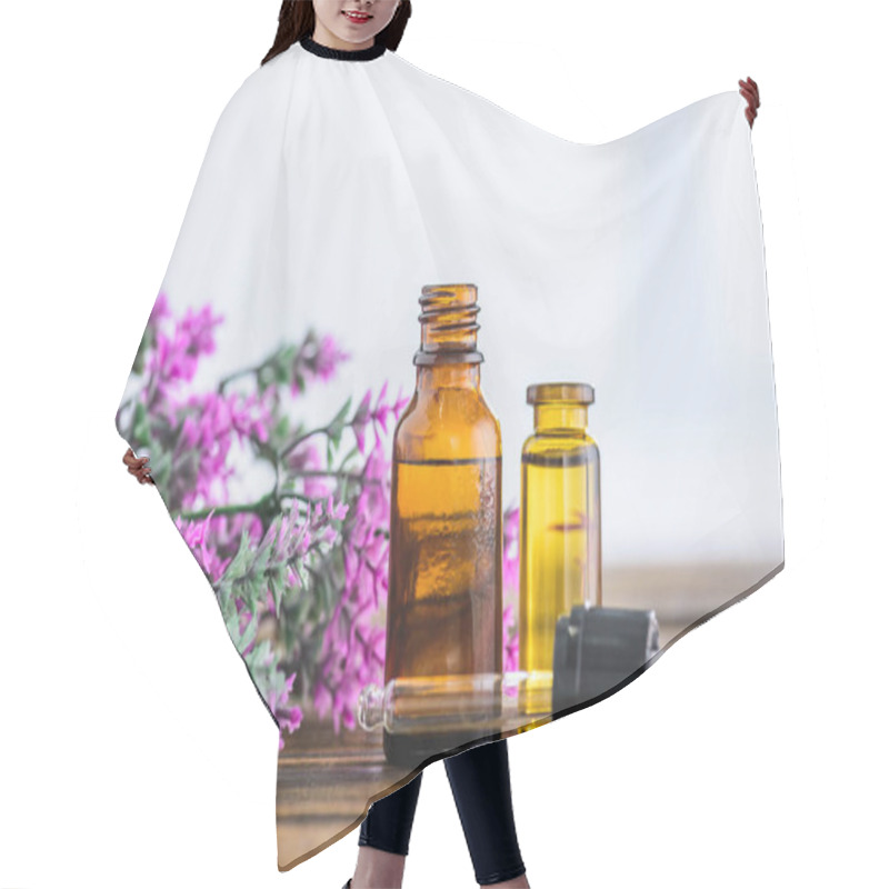 Personality  bottles with essential oils, dropper and heather flowers on white background hair cutting cape