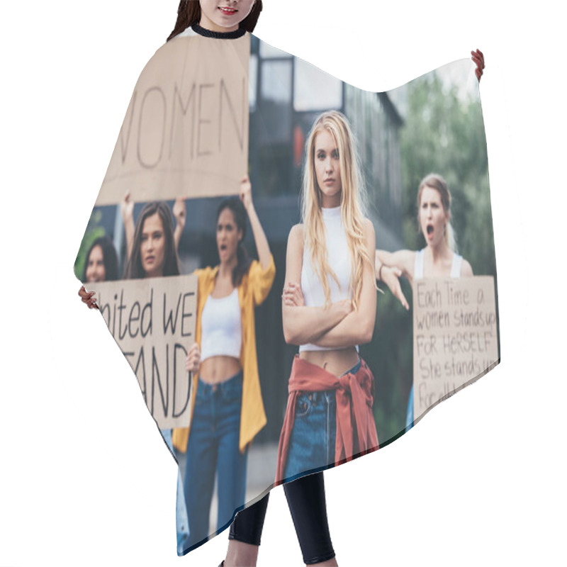 Personality  serious woman standing with arms crossed near women holding placards with feminist slogans on street hair cutting cape