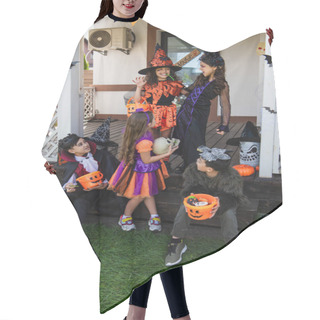 Personality  Cheerful Girl Showing Scary Gesture Near Multiethnic Friends In Halloween Costumes Hair Cutting Cape