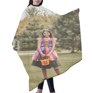 Personality  Cute Child In Halloween Costume Standing With Bucket Of Sweet Candies On Green Grass, Girl In Dress Hair Cutting Cape