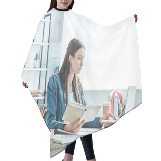 Personality  Focused Teenage Girl Holding Book And Using Laptop While Studying At Home Hair Cutting Cape