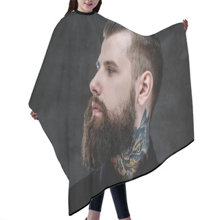 Personality  Profile Portrait Of An Expressive Bearded Man With Tattoos On His Neck, Isolated On A Dark Background. Hair Cutting Cape