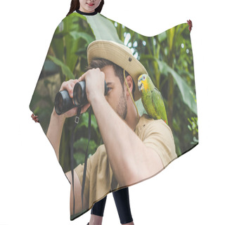 Personality  Attractive Young Man With Parrot On Shoulder Looking Through Binoculars In Jungle Hair Cutting Cape