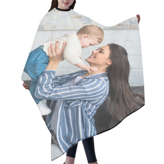 Personality  Side View Of Happy Mother With Baby In Hands Sitting On Sofa At Home Hair Cutting Cape