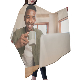 Personality  Portrait Of Young Adult Black Male Holding Morning Coffee, Smiling At Camera. Working Remotely In Modern Apartment. Hair Cutting Cape