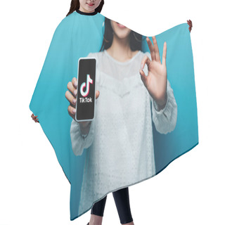 Personality  KYIV, UKRAINE - JULY 15, 2019: Cropped View Of Smiling Asian Woman In White Blouse Showing Ok Sign And Smartphone With Tiktok App On Blue Background Hair Cutting Cape