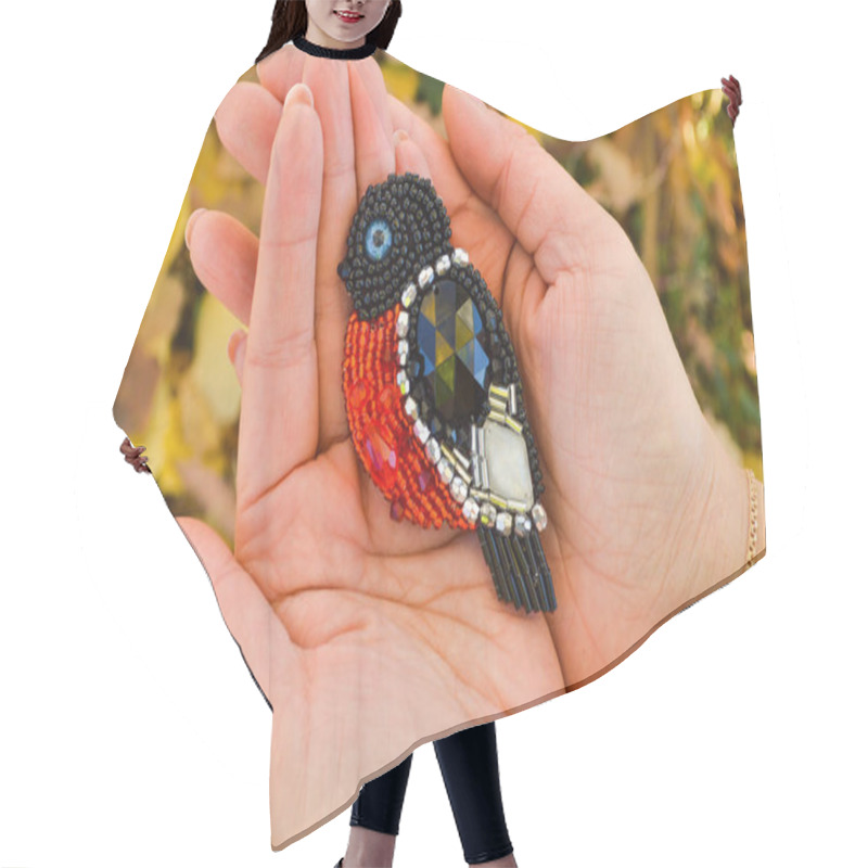 Personality  A Toy Bird, A Handmade Beaded Bullfinch Brooch, Lying On Women's Palms. The Background Is Blurred Hair Cutting Cape