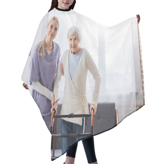 Personality  Happy Nurse And Senior Woman Looking At Camera Near Medical Walkers In Living Room Hair Cutting Cape