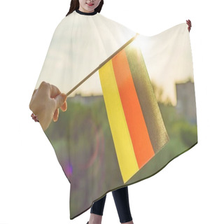 Personality  Hand Holds Germany Flag An Open Window. Background Blue Sky, Silhouette Of The City, Sunset. Hair Cutting Cape