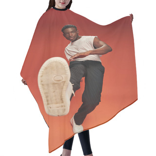 Personality  Stylish African American Man In Daring Pose With Outstretched Leg On Red And Orange Backdrop Hair Cutting Cape