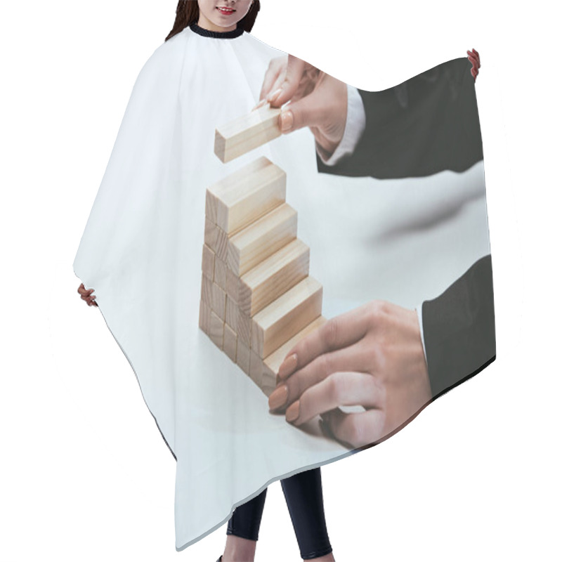 Personality  cropped view of woman putting wooden brick on top of wooden blocks symbolizing career ladder hair cutting cape