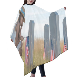 Personality  Panoramic Shot Of Kid In Straw Hat Covering Face While Sitting Near Headstones With American Flags  Hair Cutting Cape