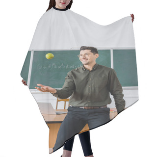 Personality  Smiling Male Teacher Throwing Apple In Class With Chalkboard And Desk On Background  Hair Cutting Cape