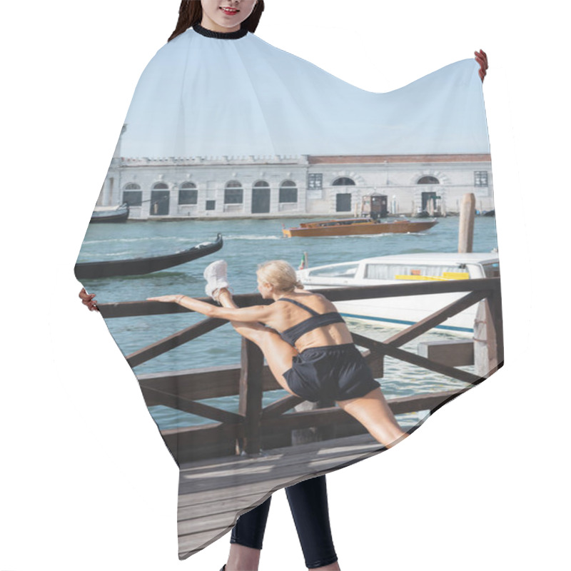Personality  Fit Sportswoman In White Sneakers, Black Crop Top And Shorts Stretching On Wooden Pier With Boats At Background In Venice  Hair Cutting Cape