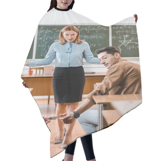 Personality  Dissatisfied Female Teacher Looking At Male Student Taking Crib During Exam In Classroom Hair Cutting Cape