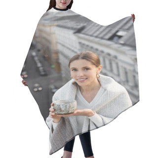 Personality  Woman Covered With Shawl Holding Clay Cup And Smiling At Camera Near Rooftops On Blurred Background Hair Cutting Cape