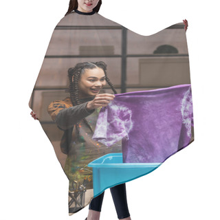 Personality  Positive African American Craftswoman Holding T-shirt In Tie Dye Style Near Box In Workshop  Hair Cutting Cape
