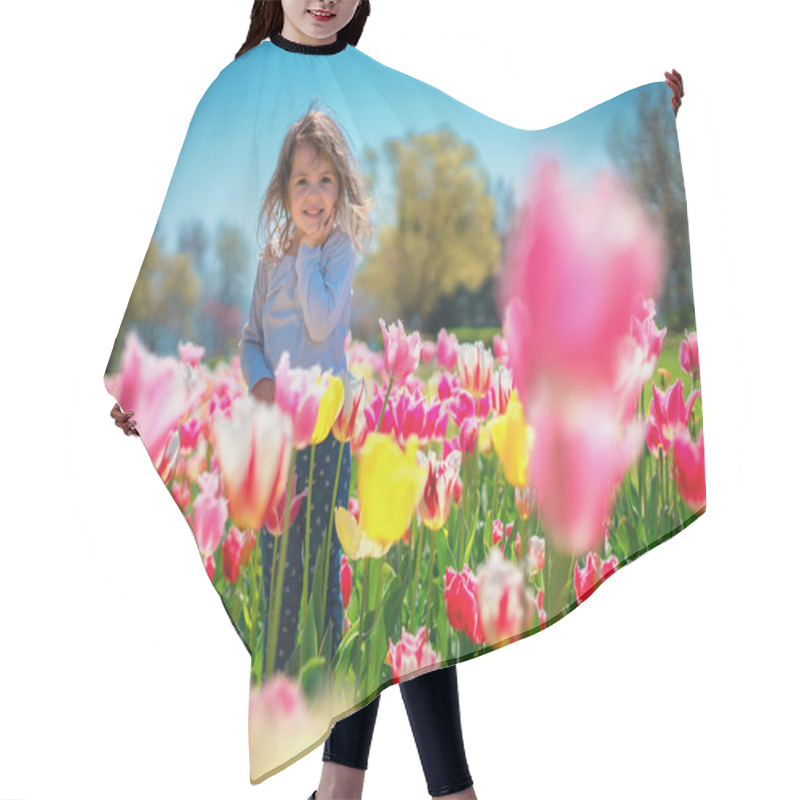 Personality  Beautiful little girl in flowers park of tulips. hair cutting cape