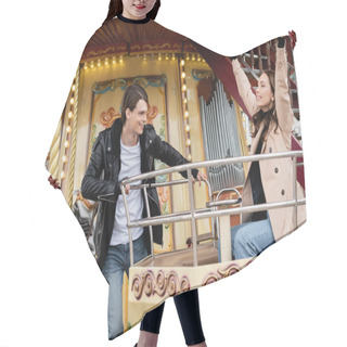 Personality  Cheerful Man In Trendy Outfit Looking At Happy Girlfriend With Raised Hands On Carousel In Amusement Park Hair Cutting Cape