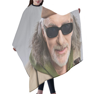 Personality  Portrait Of Smiling Senior Man With Grey Hair And Groomed Beard, In Dark Sunglasses, Beanie Hat And Trench Coat Looking At Camera On Grey Background, Hipster Fashion, Happy And Trendy Aging Concept Hair Cutting Cape