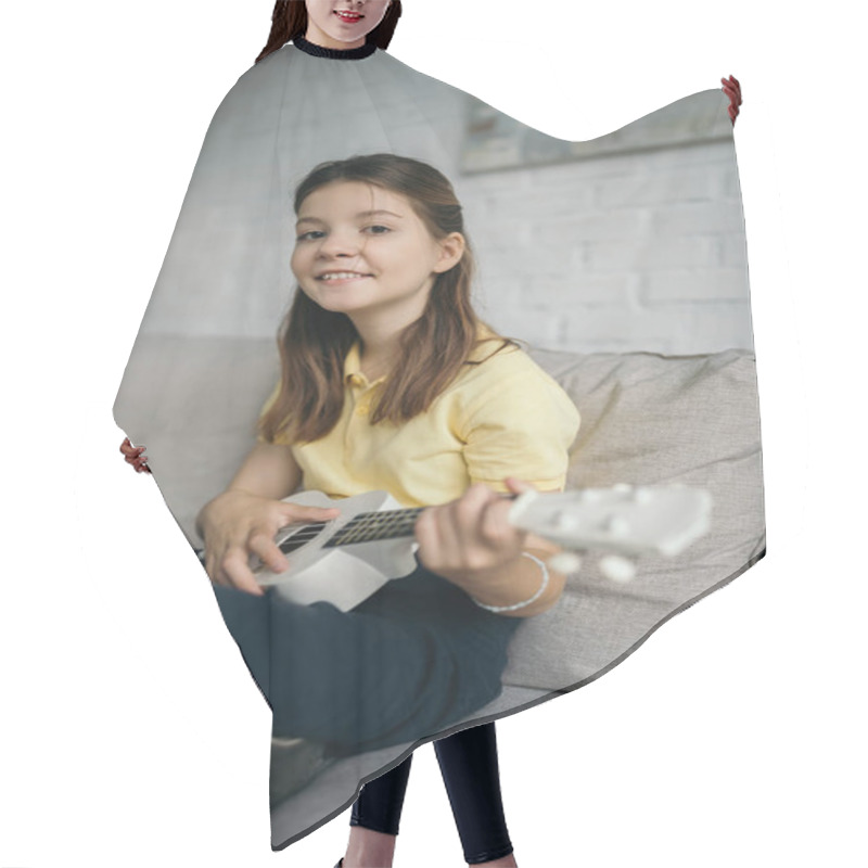 Personality  Cheerful Preteen Girl Smiling At Camera While Playing Ukulele On Sofa In Living Room Hair Cutting Cape