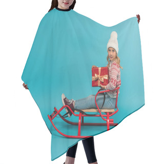 Personality  Girl In Knitted Hat And Jumper Holding Red Gift Box While Sitting In Sled On Blue Hair Cutting Cape