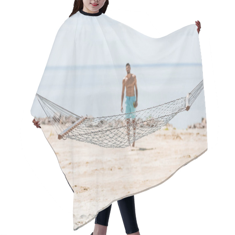 Personality  selective focus of hammock and shirtless man walking on beach on background hair cutting cape