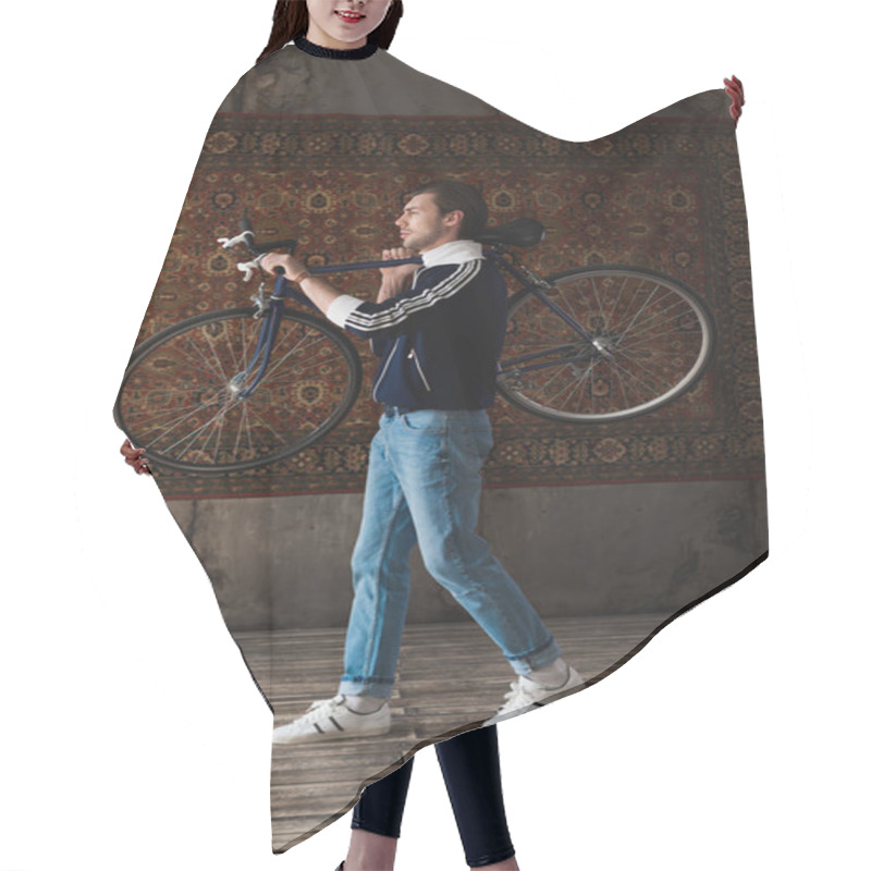 Personality  Handsome Young Man In Vintage Clothes Carrying Road Bike On Shoulder In Front Of Rug Hanging On Wall Hair Cutting Cape