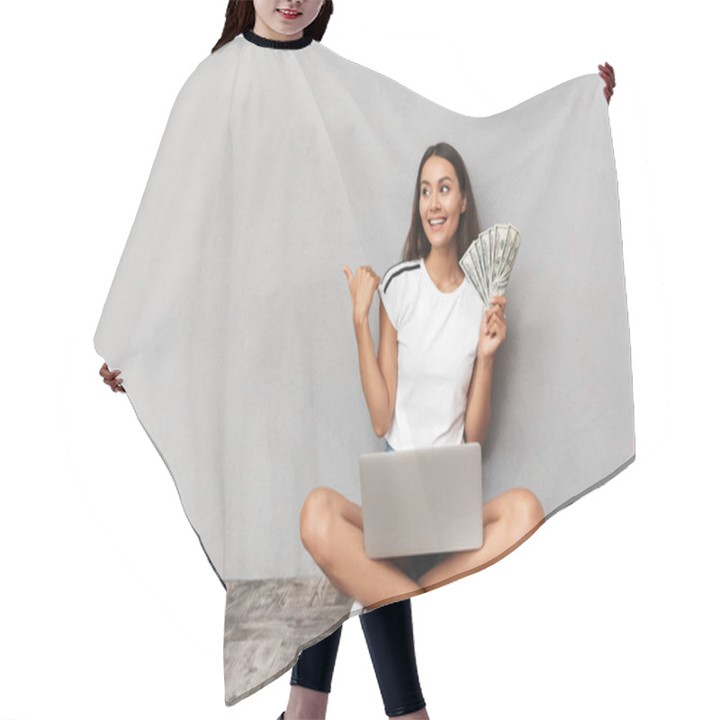 Personality  Image Of Excited Happy Young Woman Sitting Isolated Over Grey Background Using Laptop Computer Holding Money Looking Aside Pointing. Hair Cutting Cape