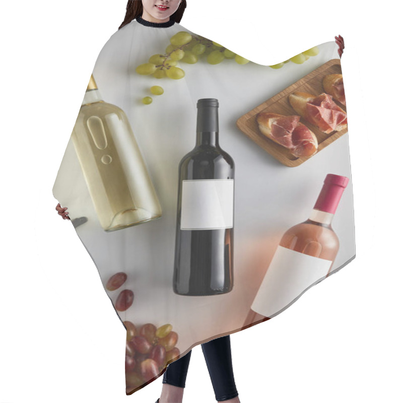 Personality  top view of bottles with white, red and rose wine near grape, corkscrew and sliced prosciutto on baguette on white background hair cutting cape