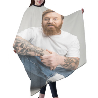 Personality  Portrait Of Tattooed Man In Jeans And T-shirt Sitting On Chair Isolated On Grey  Hair Cutting Cape