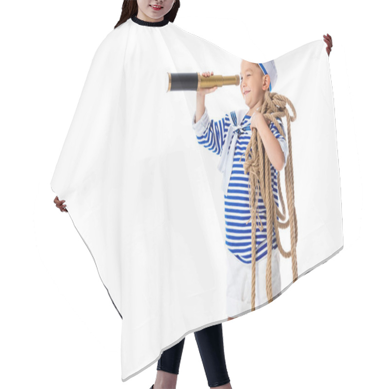 Personality  smiling preschooler child in sailor costume looking in spyglass and holding rope isolated on white hair cutting cape