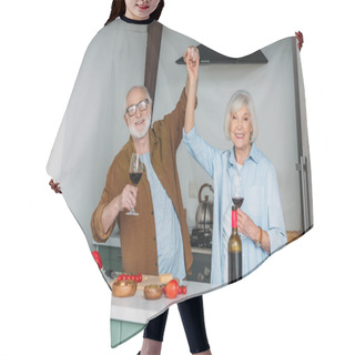 Personality  Happy Senior Couple With Wine Glasses Looking At Camera While Having Fun Near Table With Food In Kitchen Hair Cutting Cape