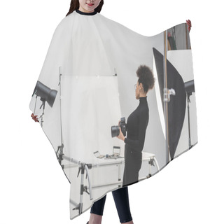 Personality  Side View Of African American Content Maker With Digital Camera Looking At Decorative Cosmetics And Beauty Tools In Photo Studio Hair Cutting Cape