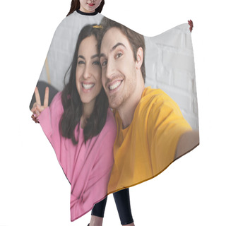 Personality  Smiling Young Couple Sitting On Couch And Looking At Camera With Victory Gesture In Living Room Hair Cutting Cape