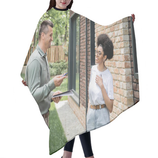 Personality  Real Estate Agent With Folder And Pen Talking To Smiling African American Client Near New Cottage Hair Cutting Cape