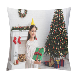 Personality  Happy Girl In Party Cap Holding Gift Box Near Blurred Christmas Tree And Fireplace At Home  Pillow Covers