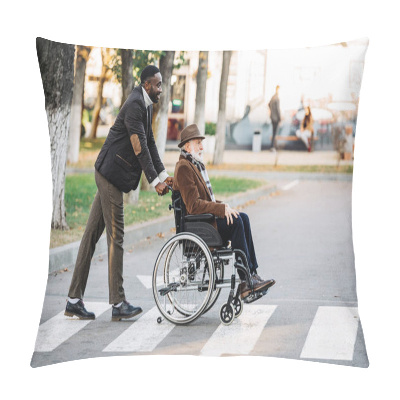 Personality  Side View Of Senior Disabled Man In Wheelchair And Young African American Cuidador Riding By Street Pillow Covers