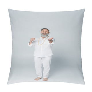 Personality  Full Length Of Pleased Yoga Coach In White Clothes Looking At Camera And Pointing With Hand On Grey Pillow Covers