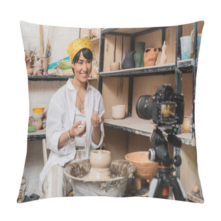 Personality  Positive Young Asian Artisan In Headscarf And Workwear Looking At Blurred Digital Camera On Tripod Near Clay On Pottery Wheel And Rack With Sculptures In Workshop, Clay Sculpting Process Concept Pillow Covers