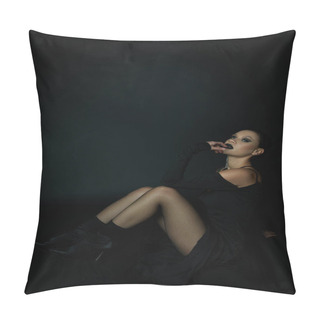 Personality  Sensual Woman In Sexy Halloween Dress And Dark Makeup Looking At Camera While Sitting On Black Pillow Covers
