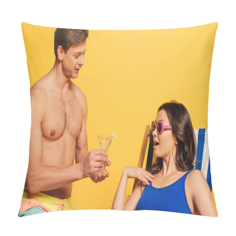 Personality  handsome shirtless man proposing glass of cocktail to surprised woman sitting in deck chair on yellow background pillow covers