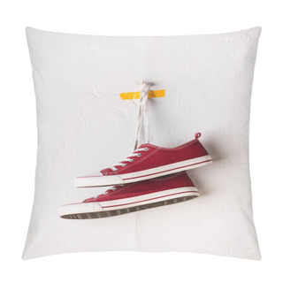 Personality  Casual Red Sneakers Hanging On Shoelaces Near White Textured Wall Pillow Covers